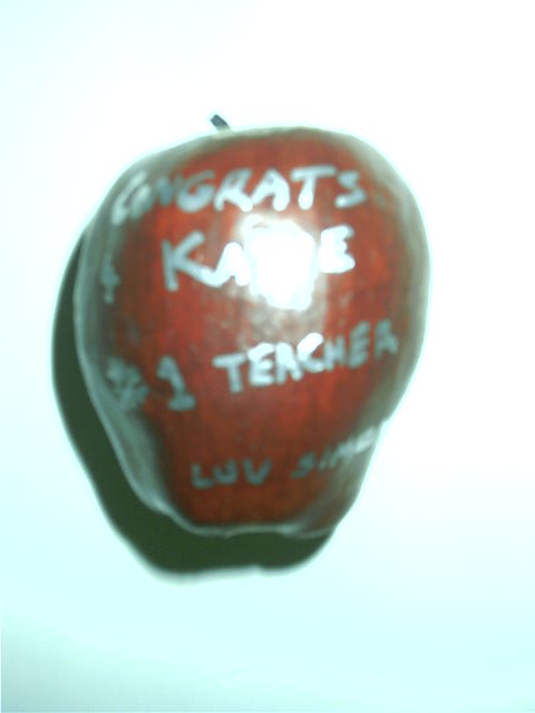 It's an apple with silver paint saying 'congrats' on becoming a teacher.